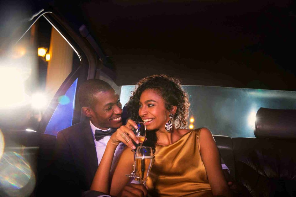 A couple in a limousine toasting with champagne glasses, celebrating a special occasion together.