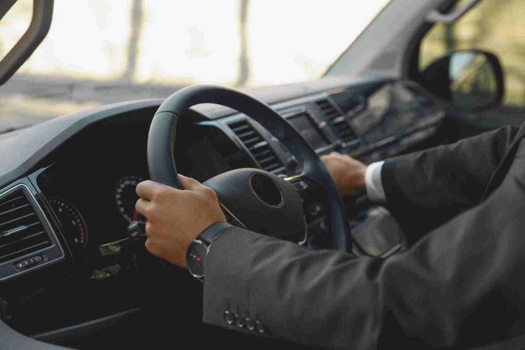 A man in a suit confidently driving a car, showcasing professionalism and focus on the road ahead.