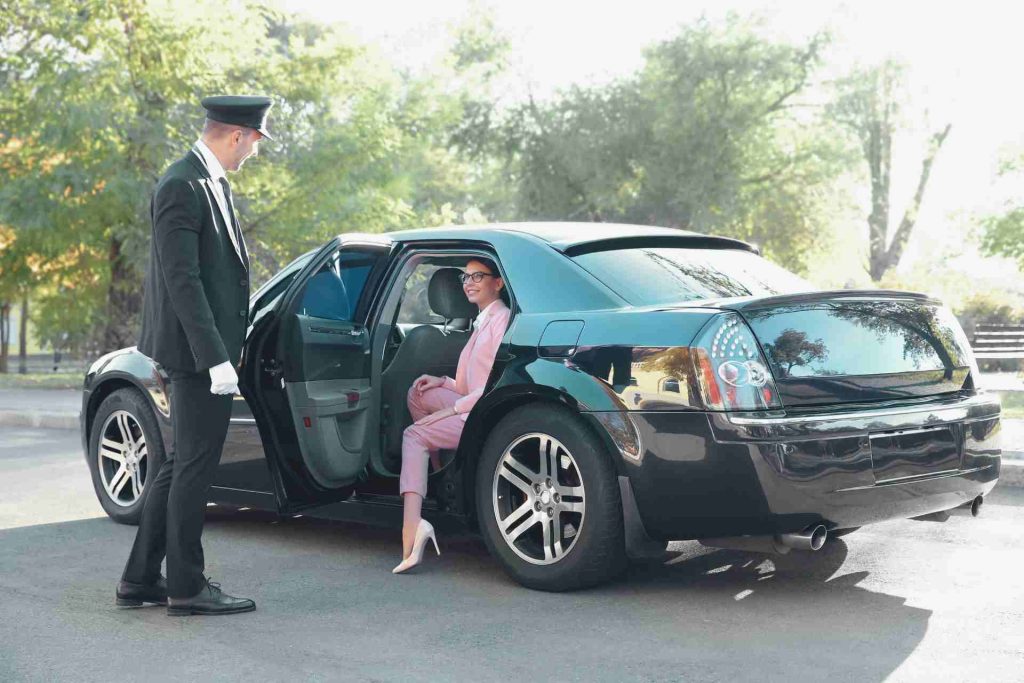 A man and woman entering a sleek black limousine.