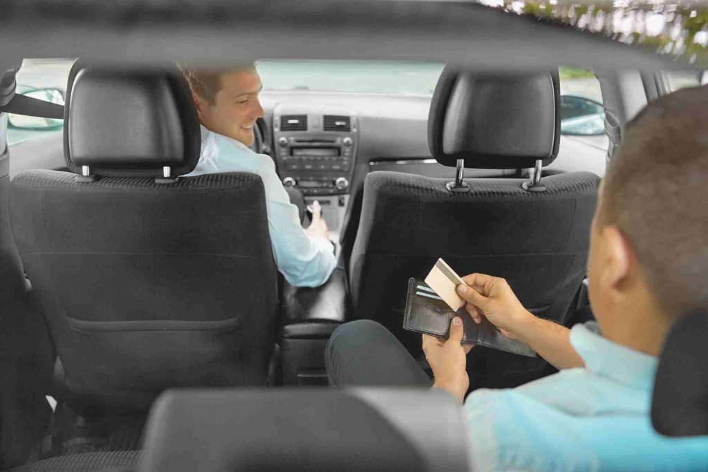 Two men seated in the car, engaged in conversation.